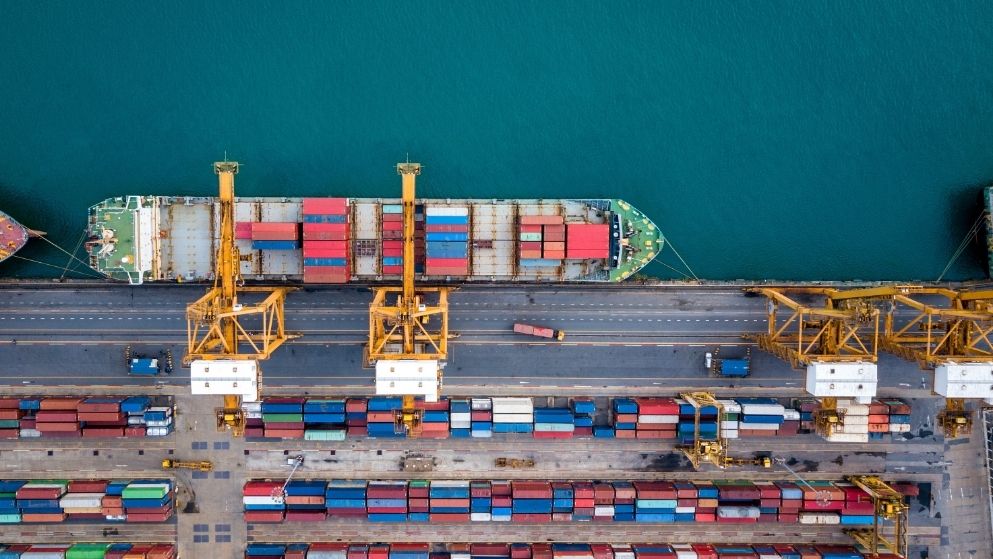 An aerial view of a cargo ship at a dock loaded with containers