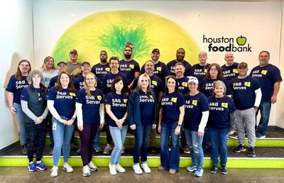 S&B Volunteers taking a group photo in front of a mural at the Houston FoodBank