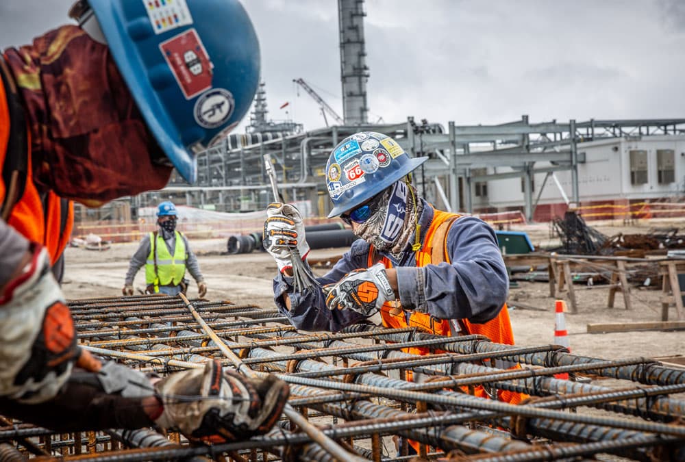 Two S&B workers tightening pipes with safety gloves and masks on