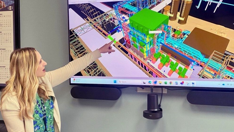 S&B Engineers and Constructors' Sophie Dupree reviews engineering schematics on a large TV screen in a conference room.