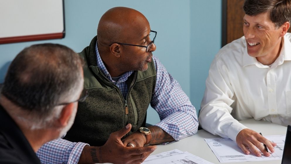 An S&B dedicated engineering team gathered around a table reviewing client documentation to on a capital project